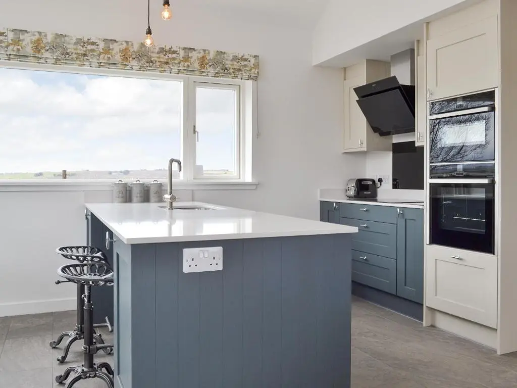 a kitchen with a blue island and a window at Muirtown Lodge in Keith