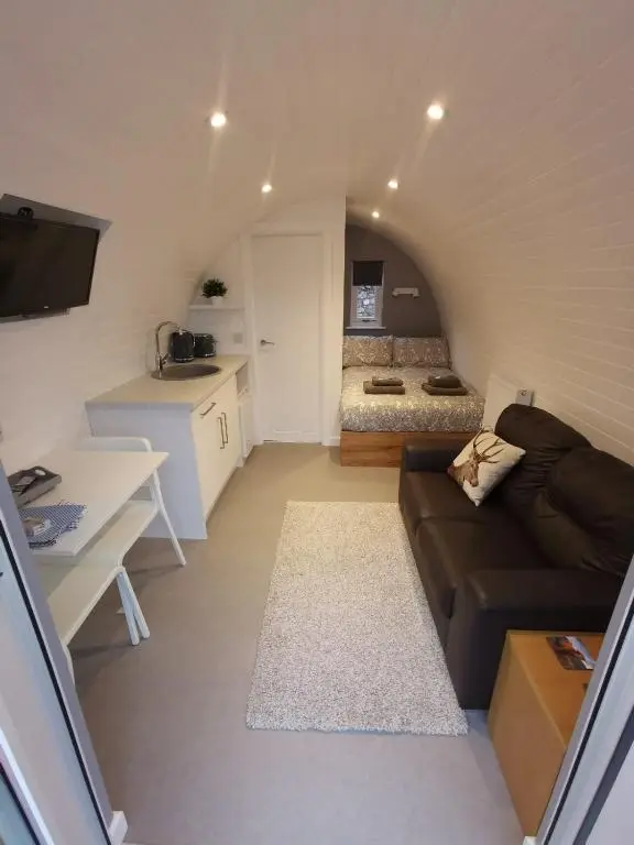 a small living room with a couch and a kitchen at Loch Ness Pods in Fort Augustus