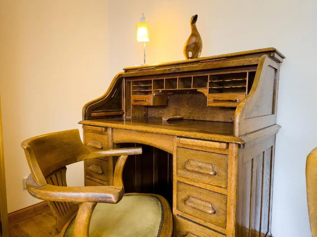 an old wooden desk with a chair and a lamp at Dalfern Lodge in Aviemore