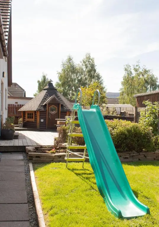 a green slide in a yard with a house at Dalfern Lodge in Aviemore