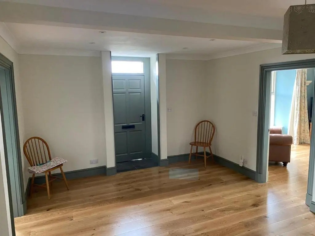 an empty living room with two chairs and a door at Granite Cottage in Nethy Bridge