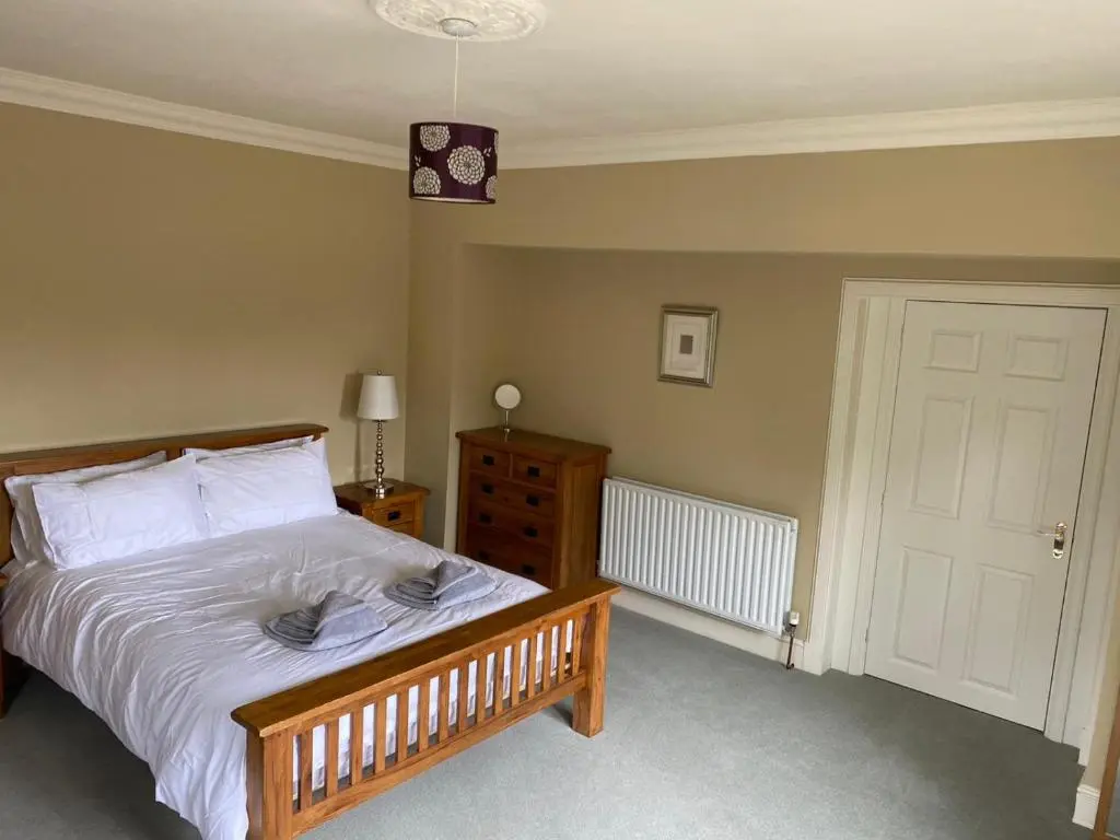 a bedroom with a bed with white sheets and a door at Granite Cottage in Nethy Bridge