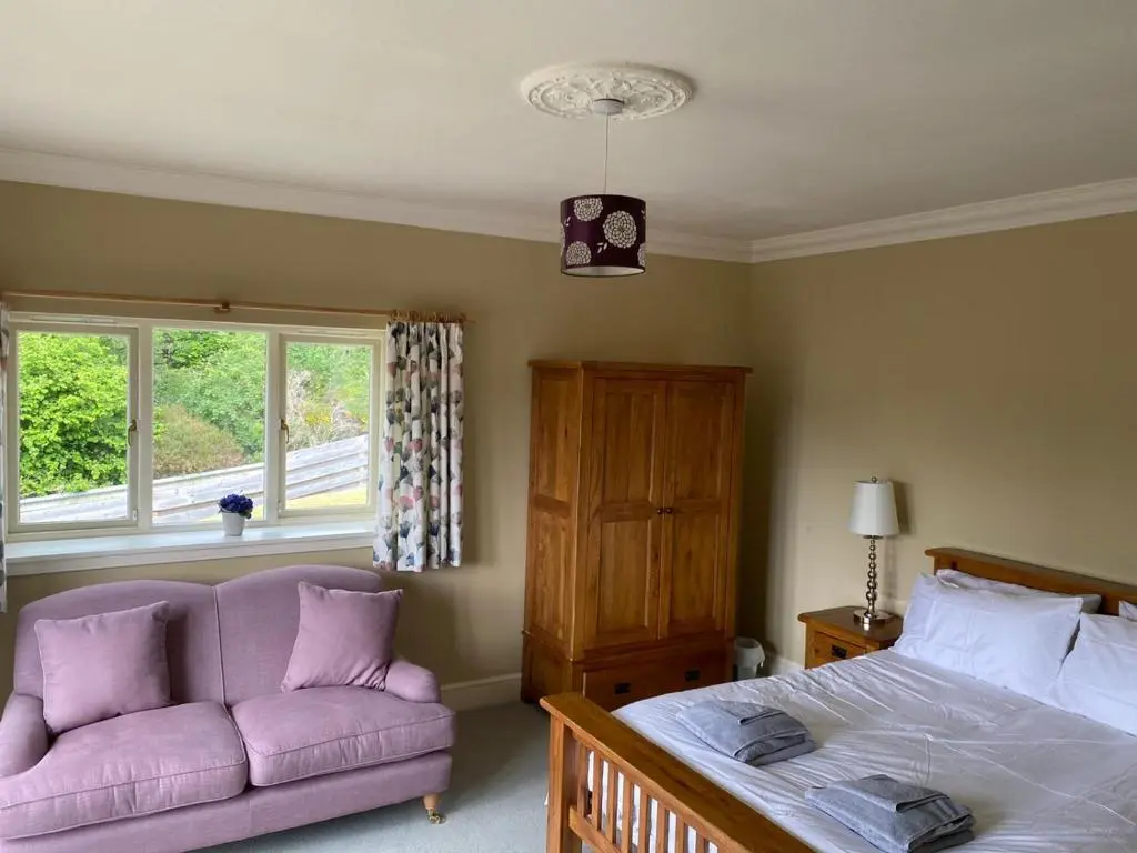 a bedroom with a bed and a couch and a window at Granite Cottage in Nethy Bridge