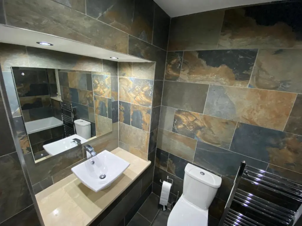 a bathroom with a sink and a toilet and a mirror at Granite Cottage in Nethy Bridge