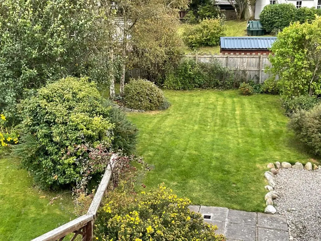 a garden with a wooden bench in a yard at Granite Cottage in Nethy Bridge