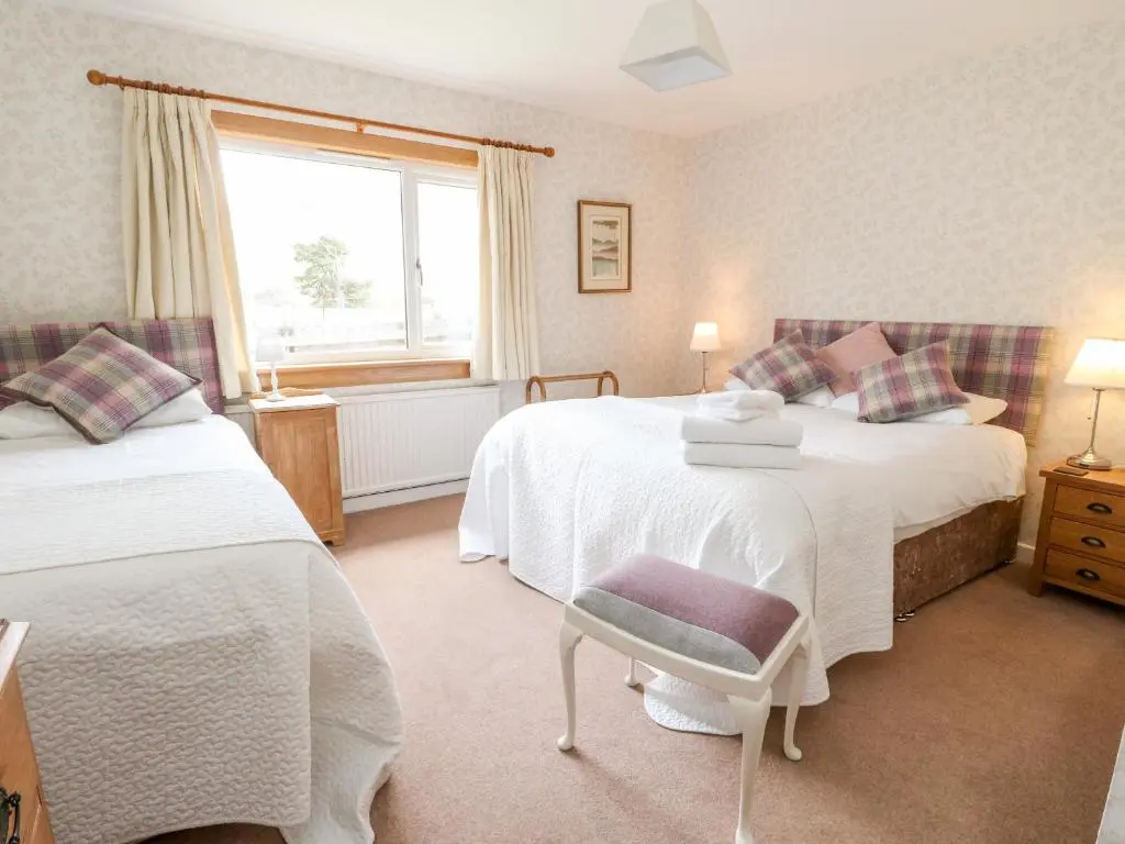 a bedroom with two beds and a window at Beechwood Cottage in Pitlochry