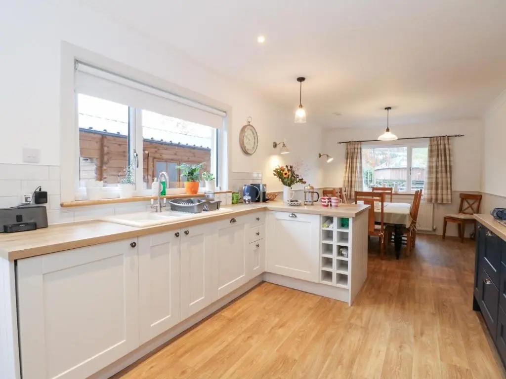 a kitchen with white cabinets and a large window at Beechwood Cottage in Pitlochry