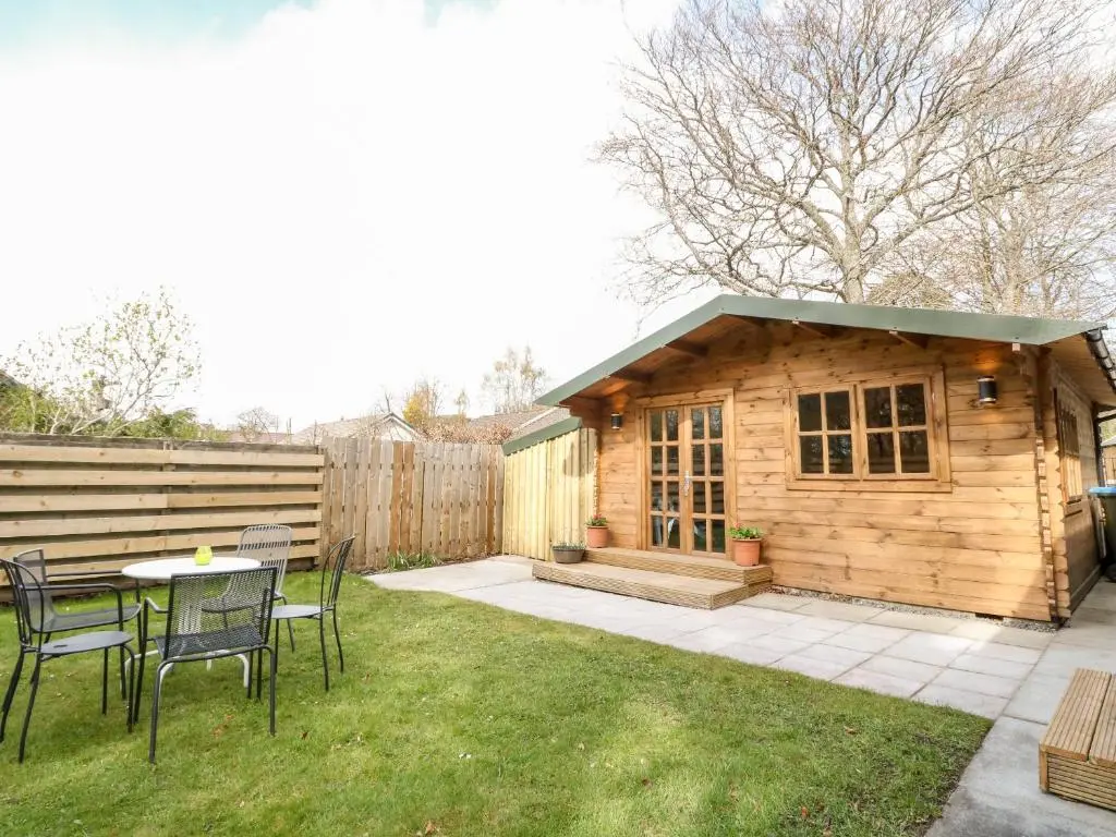 a small cabin with a table and chairs in a yard at Beechwood Cottage in Pitlochry