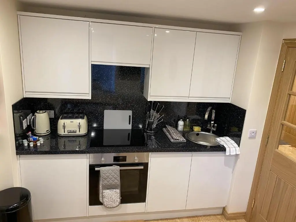 a kitchen with white cabinets and a sink at Waverley Inn Holiday Apartments in Inverness