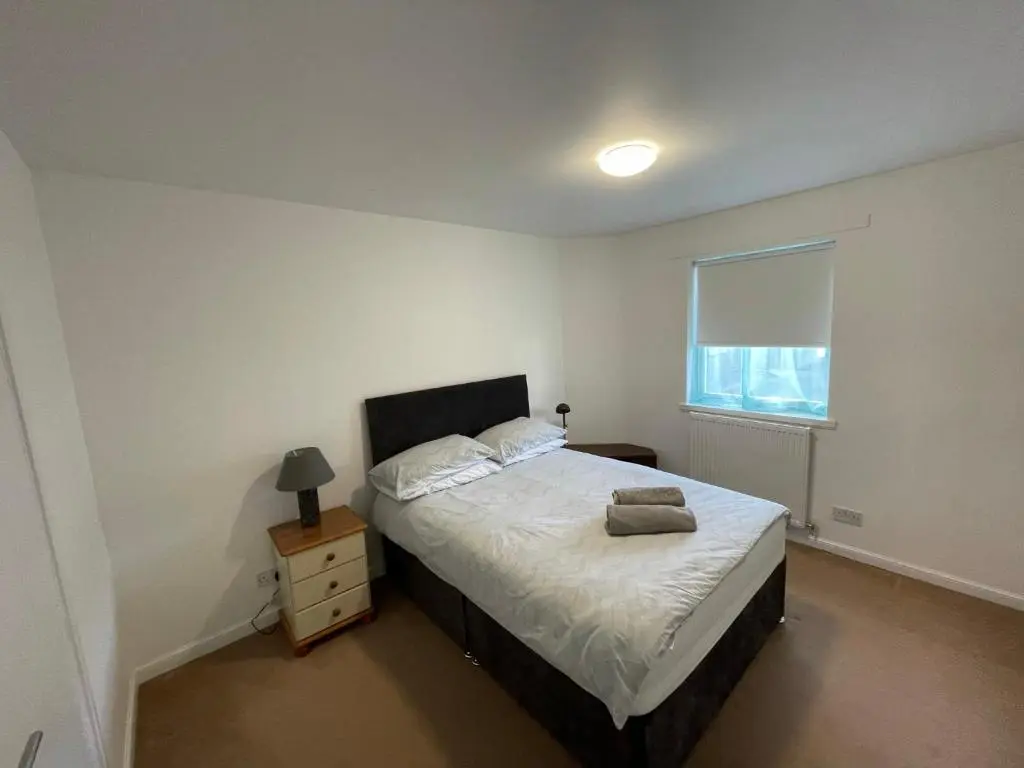 a bedroom with a large bed and a window at Lesmurdie Court, Serviced Accommodation Moray in Elgin