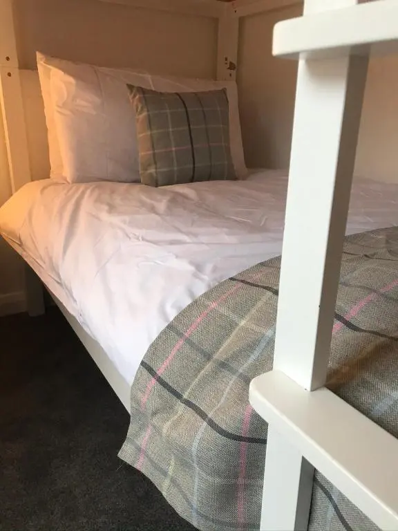 a bunk bed with white sheets and a pillow at Thistle House in Inverness