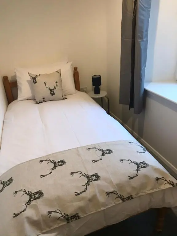 a bedroom with a bed with a blanket on it at Thistle House in Inverness