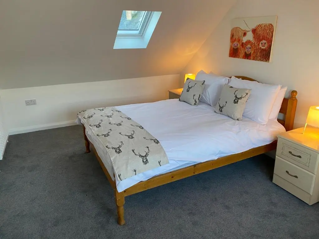 a bedroom with a bed with white sheets and pillows at Thistle House in Inverness