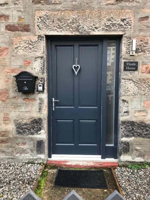 a blue door in a stone building with a heart handle at Thistle House in Inverness