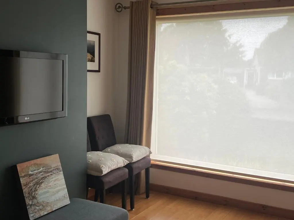 a living room with a large window and two chairs at Balnakyle in Inverness