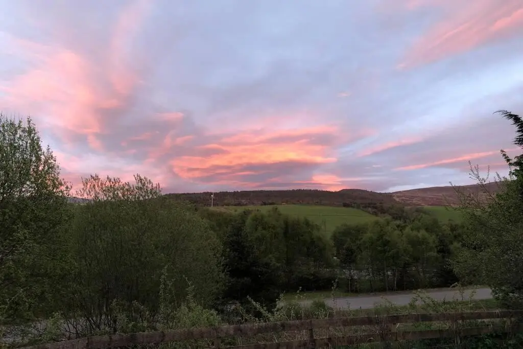 a sunset over a field with trees and a road at The Annex at Bonnieview in Inverness