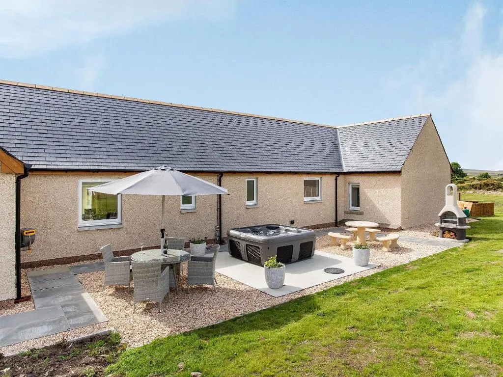 a backyard with a barbecue grill and a house at Morven View in Dunbeath