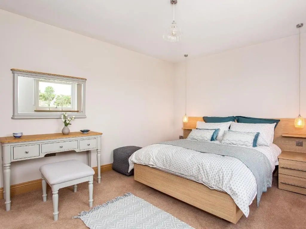 a bedroom with a bed and a desk and a window at Morven View in Dunbeath