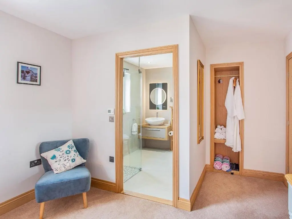 a bathroom with a shower and a chair and a mirror at Morven View in Dunbeath