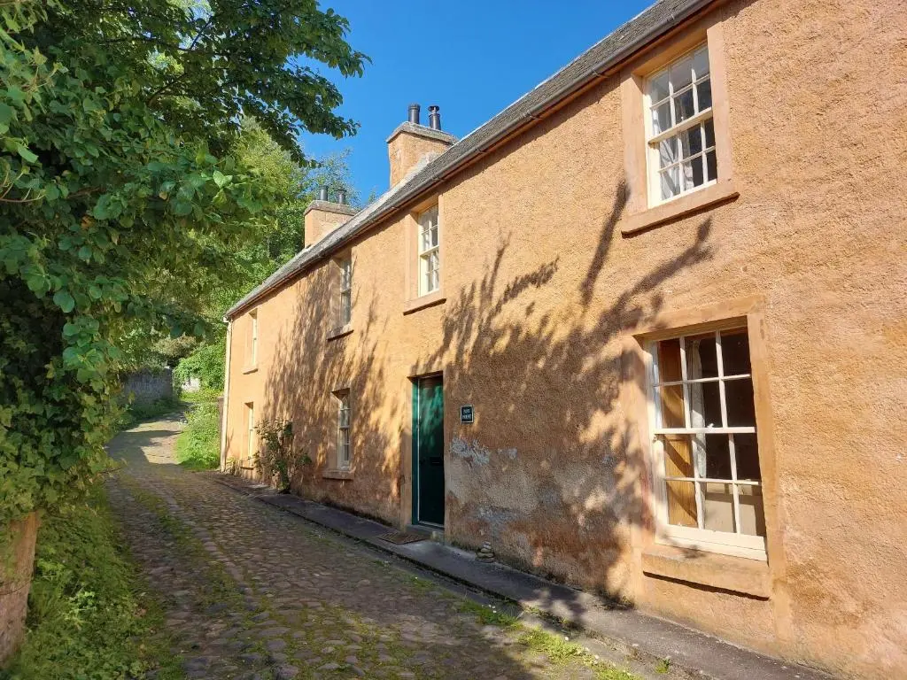 an old brick building with a green door on a street at Paye House - Cromarty in Cromarty