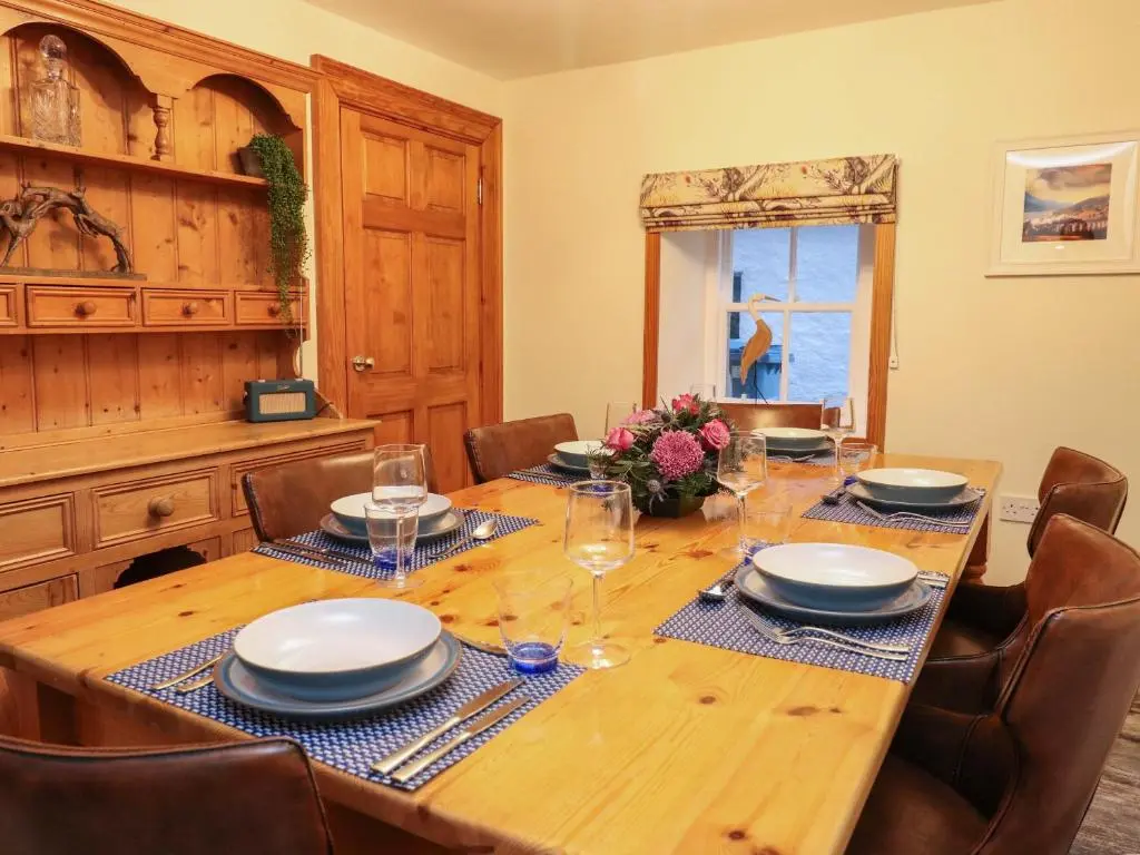 a dining room table with plates and wine glasses at Paye House - Cromarty in Cromarty