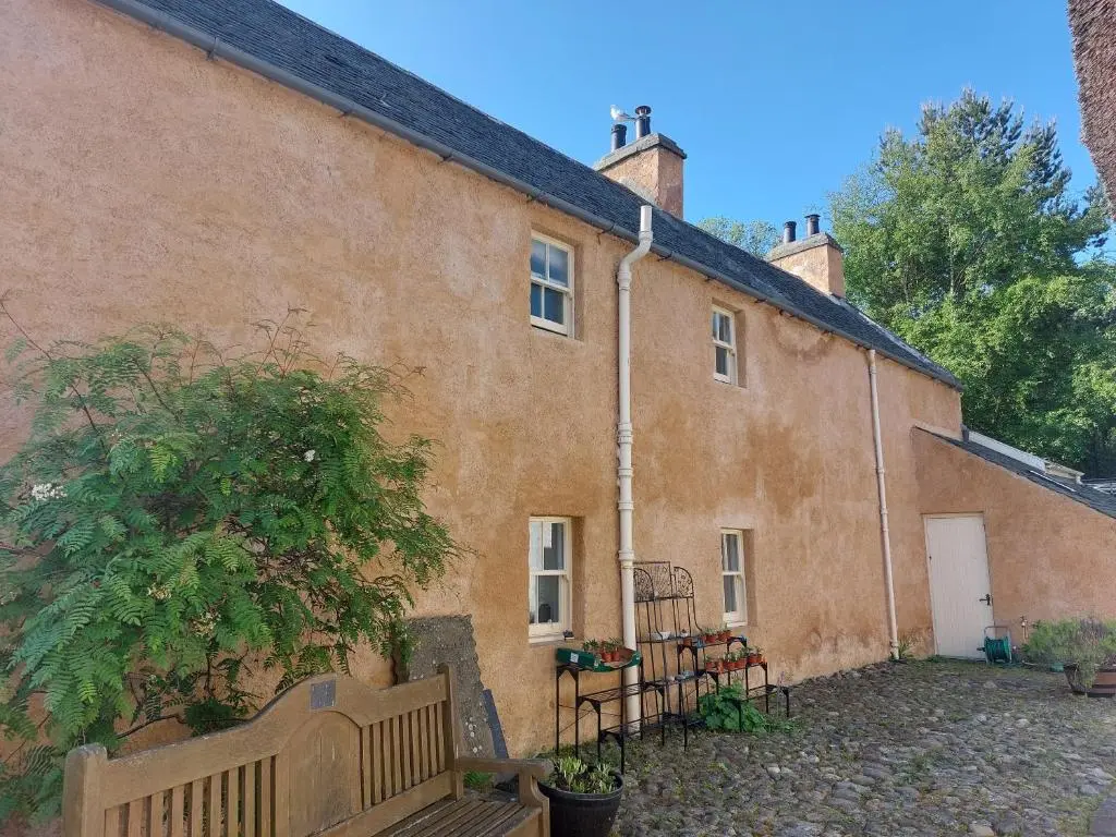 a large brick building with a bench in front of it at Paye House - Cromarty in Cromarty