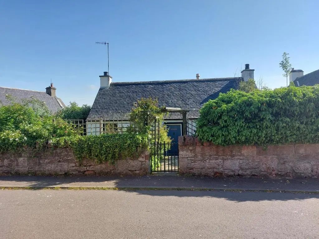 a house with a blue door and a fence at Lydia Cottage - Cromarty in Cromarty