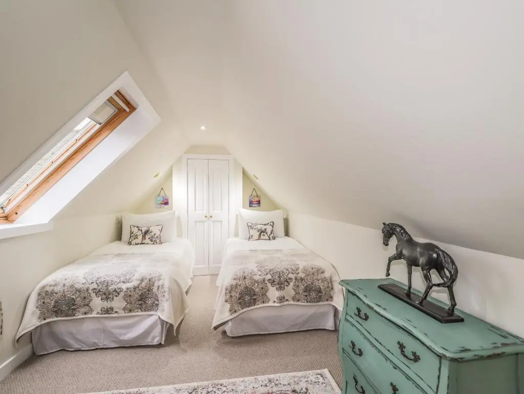 a attic bedroom with two beds and a horse statue on a dresser at Lydia Cottage - Cromarty in Cromarty