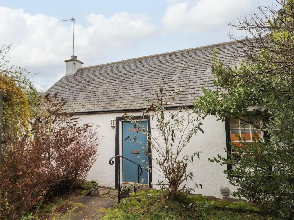 an old white cottage with a blue door at Lydia Cottage - Cromarty in Cromarty
