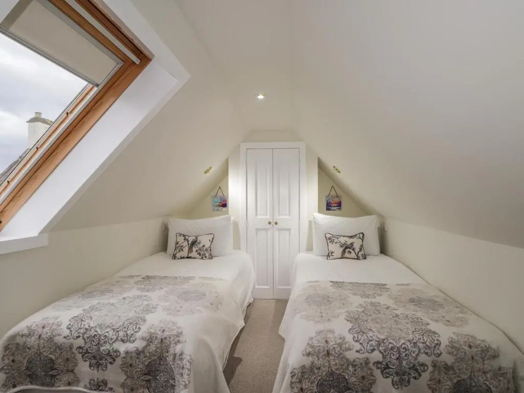 two beds in a attic room with a window at Lydia Cottage - Cromarty in Cromarty