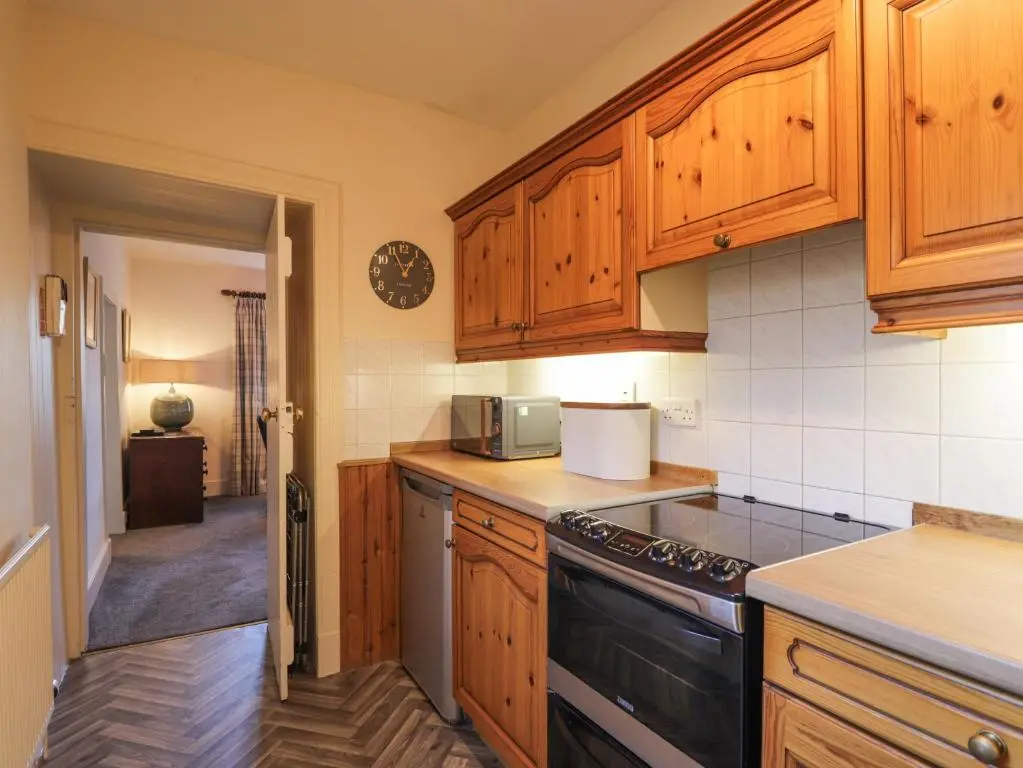 a kitchen with wooden cabinets and a stove top oven at Cormack Lodge - Brodie Castle in Forres