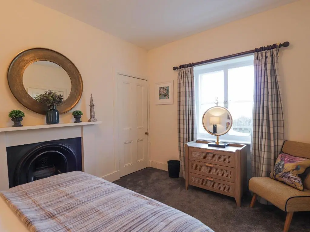 a bedroom with a bed and a mirror and a chair at Cormack Lodge - Brodie Castle in Forres