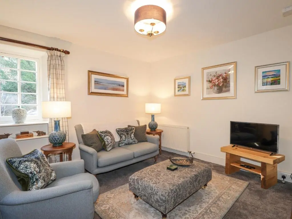 a living room with a couch and a tv at Cormack Lodge - Brodie Castle in Forres