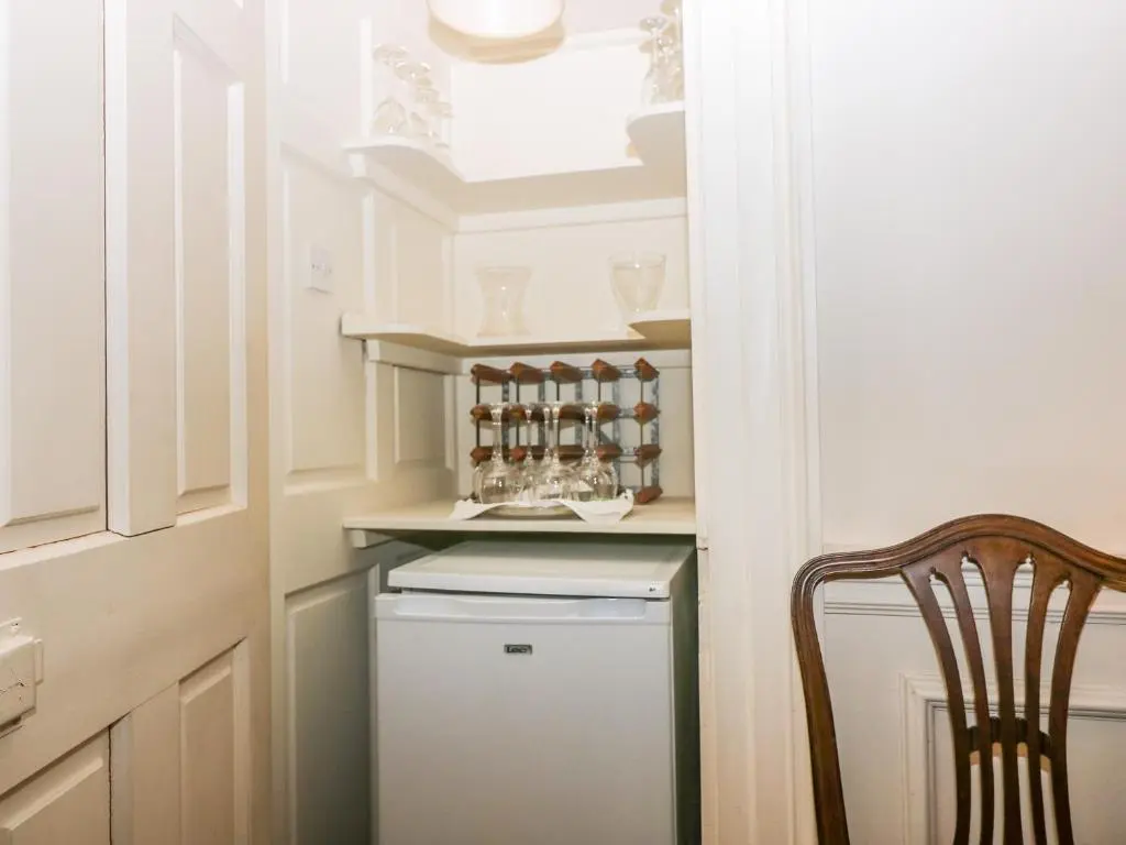 a small kitchen with a small refrigerator and a chair at The Preston Tower Apartment - Fyvie Castle in Turriff