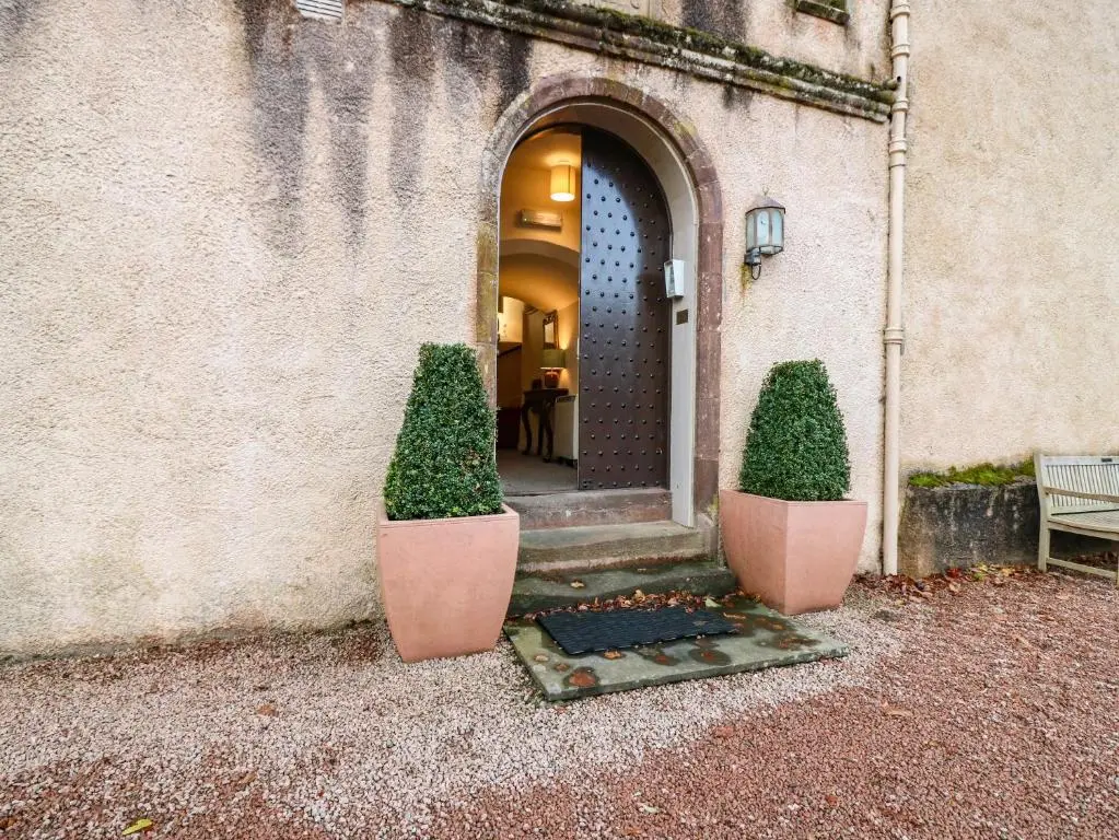 an entrance to a building with two bushes in pots at The Preston Tower Apartment - Fyvie Castle in Turriff