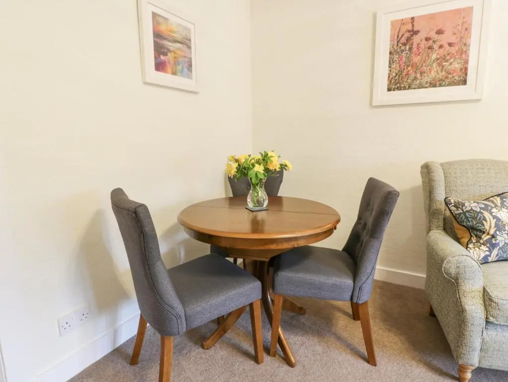 a table with two chairs and a vase of flowers on it at Beechgrove Cottage - Pitmedden Gardens in Ellon
