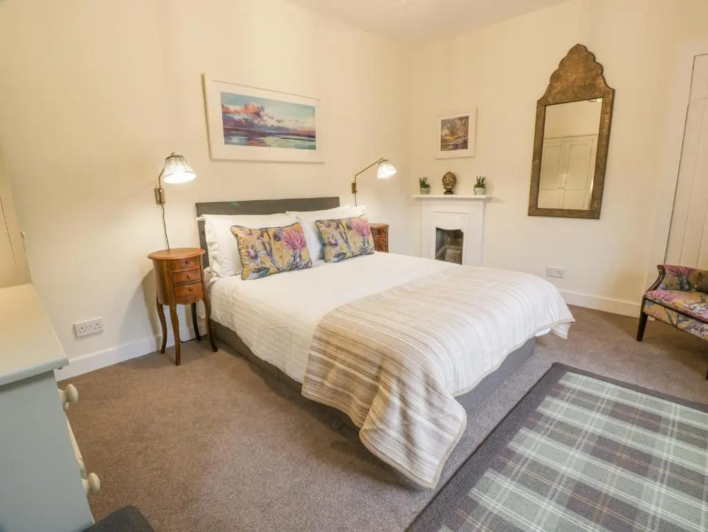 a bedroom with a large bed and a fireplace at Beechgrove Cottage - Pitmedden Gardens in Ellon