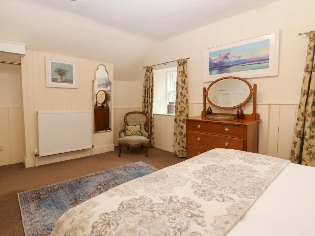 a bedroom with a bed and a dresser and a mirror at North Mains Cottage - Craigievar Castle in Alford