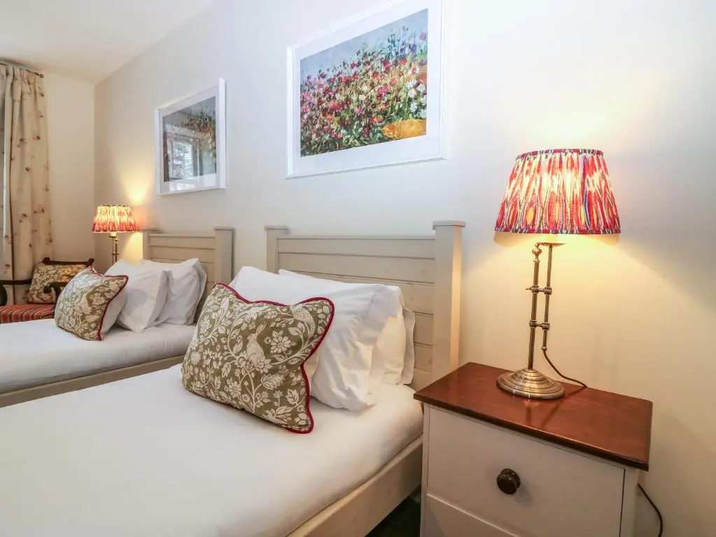 a bedroom with two beds and a lamp on a night stand at Steading Cottage - Craigievar Castle in Alford