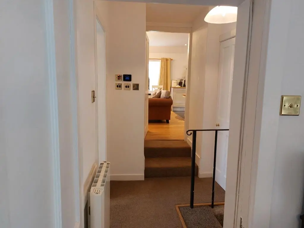 a hallway with a stairway leading to a living room at Courtyard Cottage - Drum Castle in Banchory