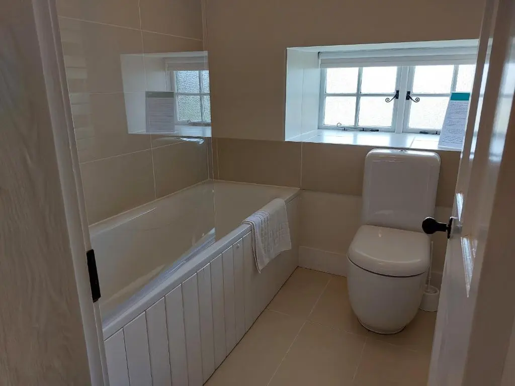 a bathroom with a tub and a toilet and a window at Courtyard Cottage - Drum Castle in Banchory