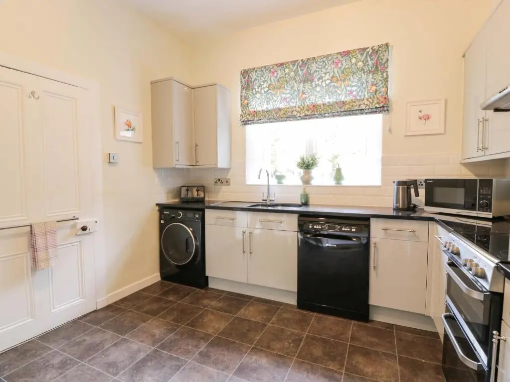 a kitchen with white cabinets and a black dishwasher at East Lodge - Crathes Castle in Banchory