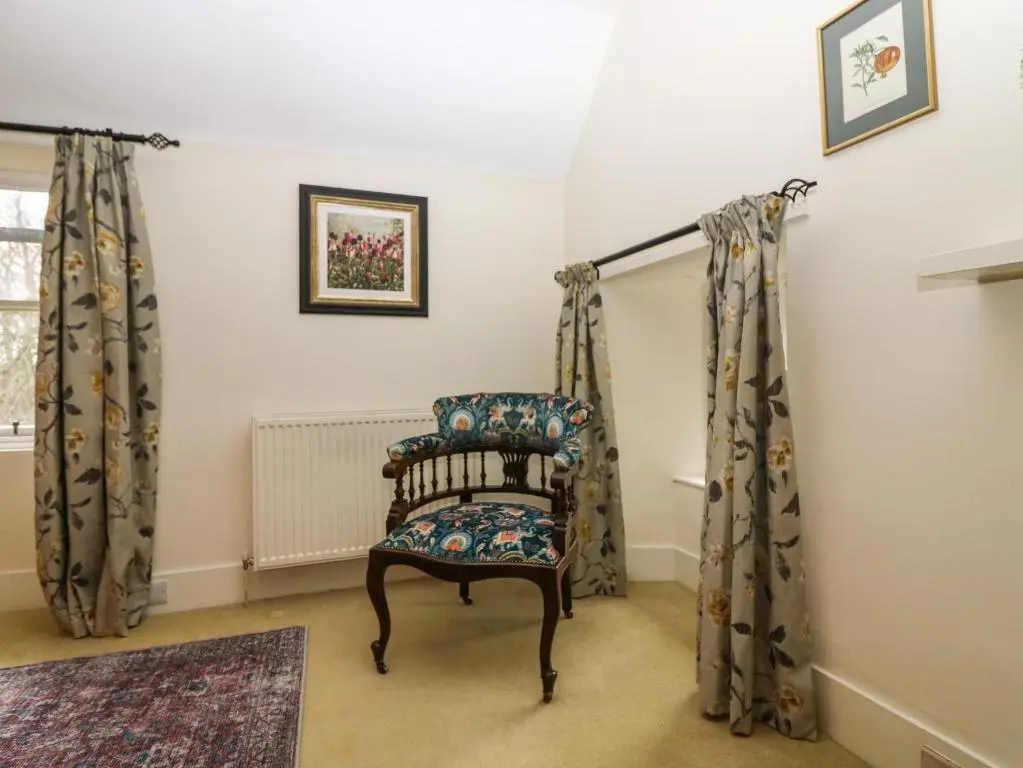 a chair in a room with curtains at South Mains Cottage - Craigievar Castle in Alford