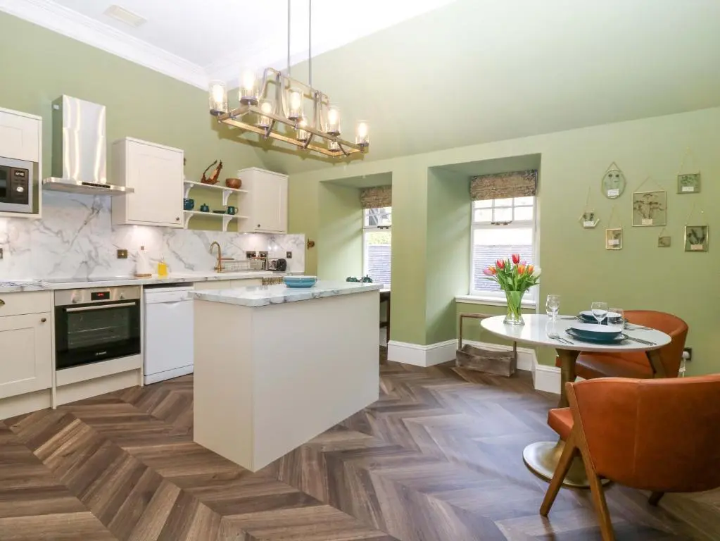 a kitchen with green walls and a table and chairs at Braeriach - Mar Lodge Estate in Ballater