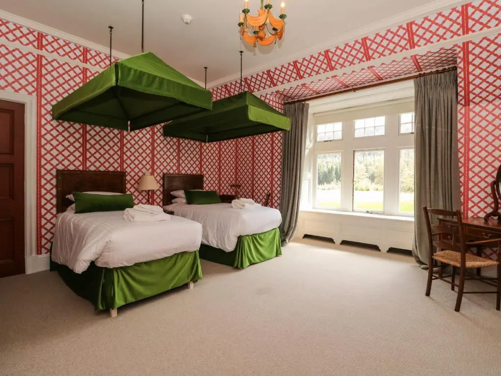 a bedroom with two beds and a chandelier at Dalvorar - Mar Lodge Estate in Ballater