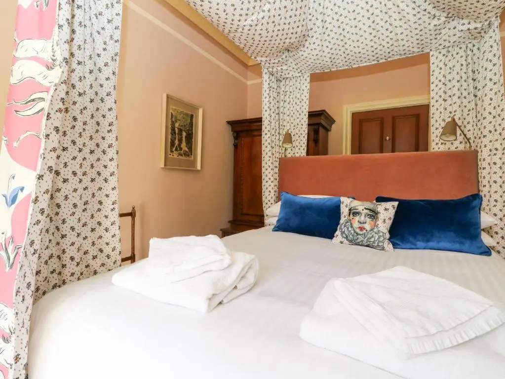 a bedroom with a large white bed with blue pillows at Dalvorar - Mar Lodge Estate in Ballater