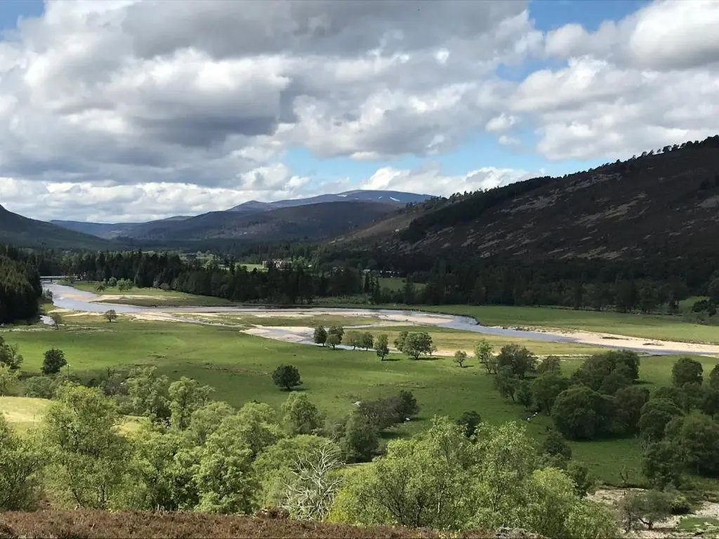 a view of a river in a field with trees at Dalvorar - Mar Lodge Estate in Ballater