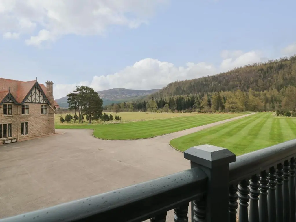 a view from a balcony of a house and a field at Macdui - Mar Lodge Estate in Ballater