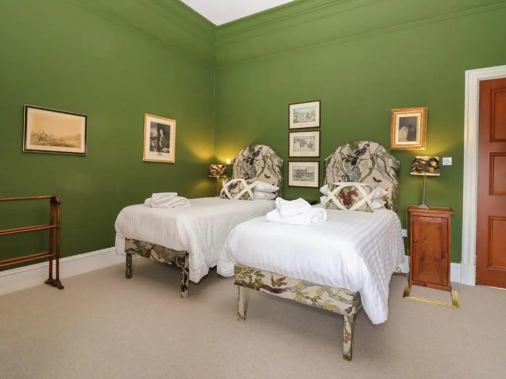 a green bedroom with two beds and two chairs at Macdui - Mar Lodge Estate in Ballater