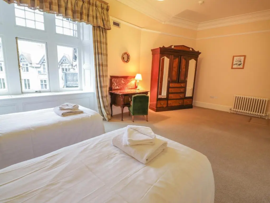 a bedroom with two beds and a desk and a window at Bynack - Mar Lodge Estate in Ballater